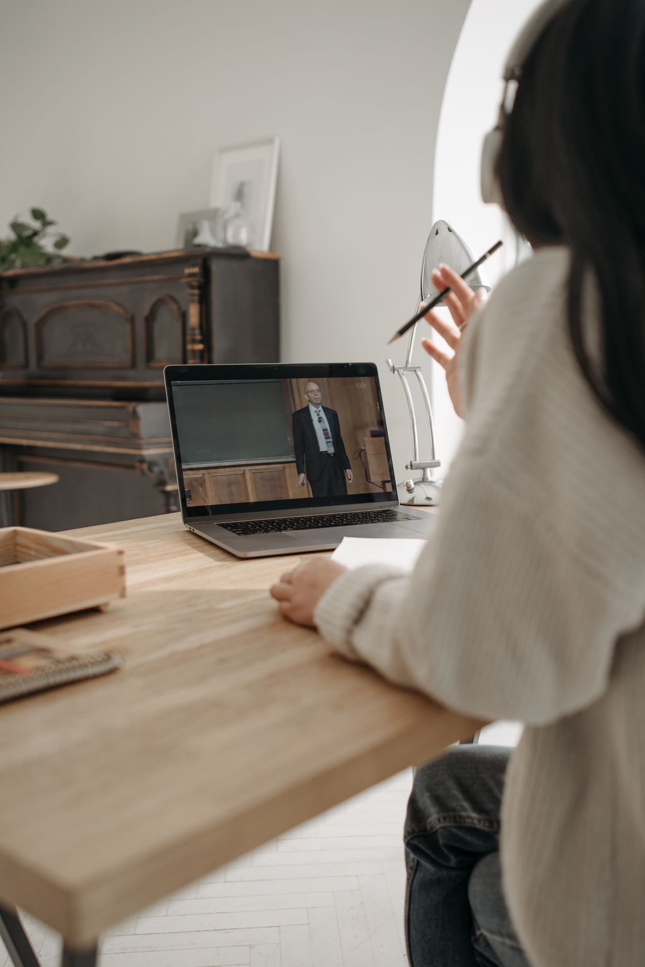 Beginner taking an online AI certification course at home with headphones and a notebook