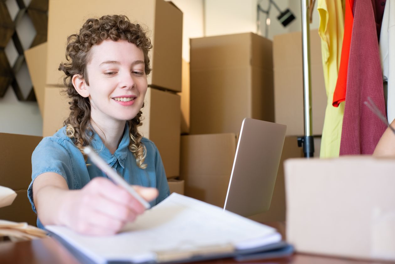 Smiling small business owner working on a laptop surrounded by parcels