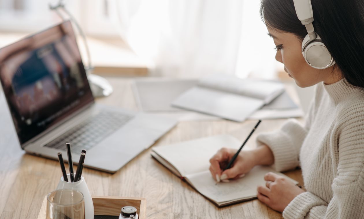 Beginner taking notes during an online AI certification course at home