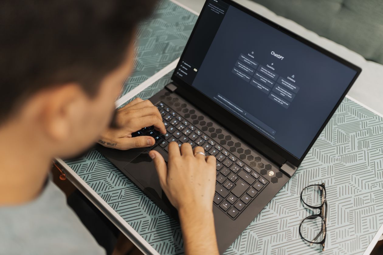 Man in glasses using an AI assistant on his laptop