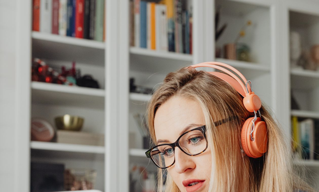 Woman with glasses and headphones taking a free online AI course on her laptop