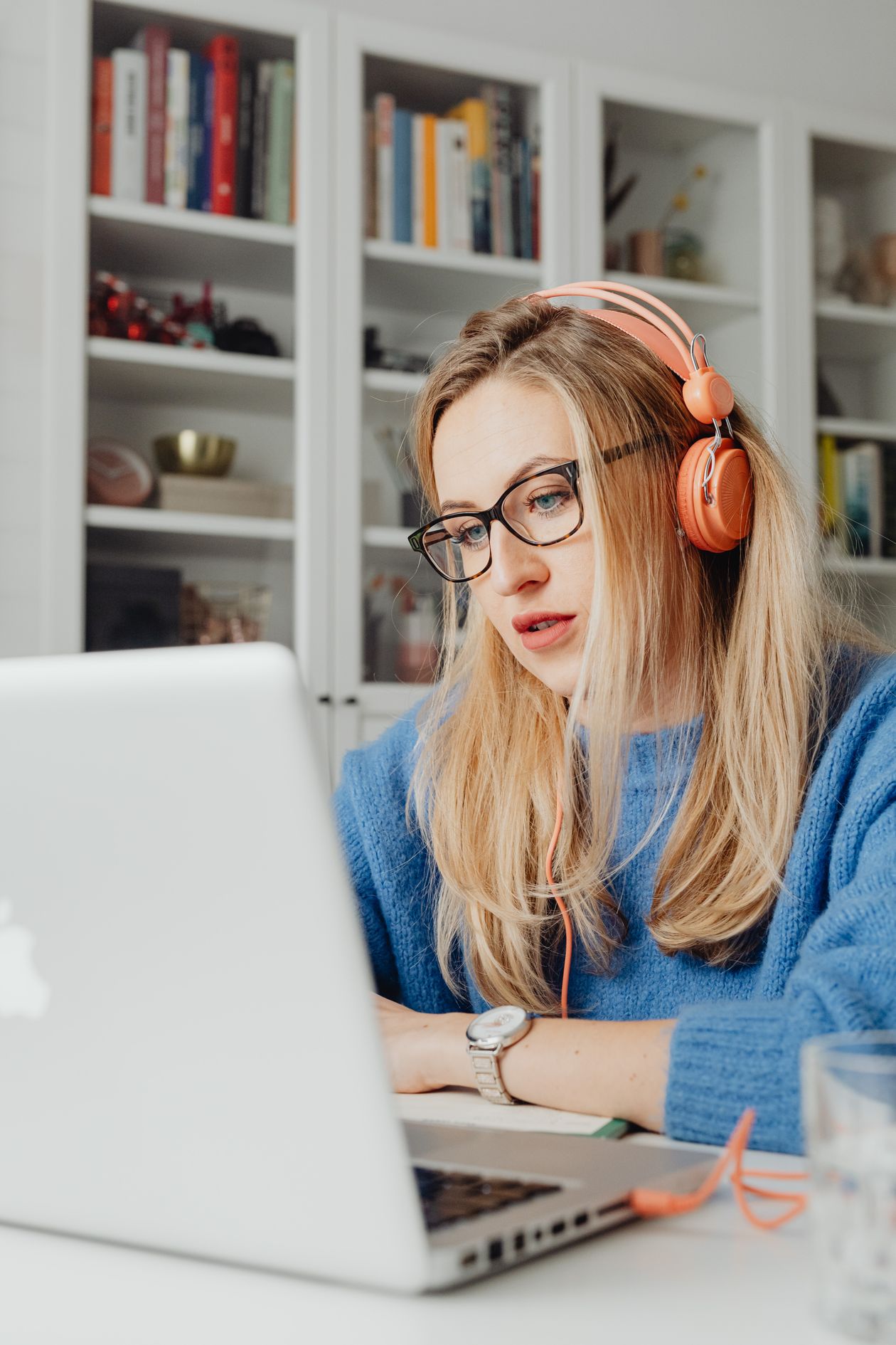 Woman with glasses and headphones taking a free online AI course on her laptop