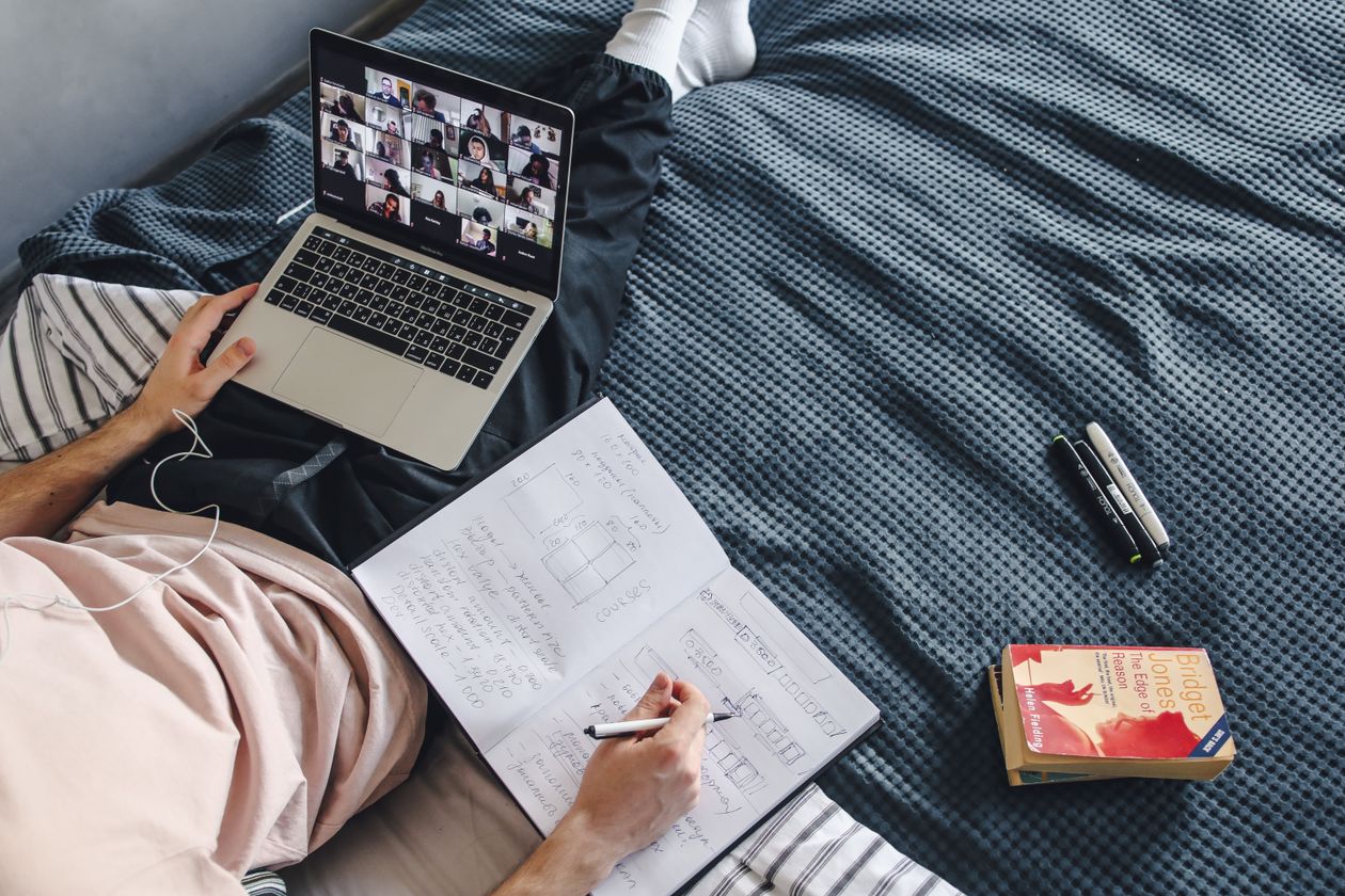 Adult taking an online AI course on a laptop with a notebook at home
